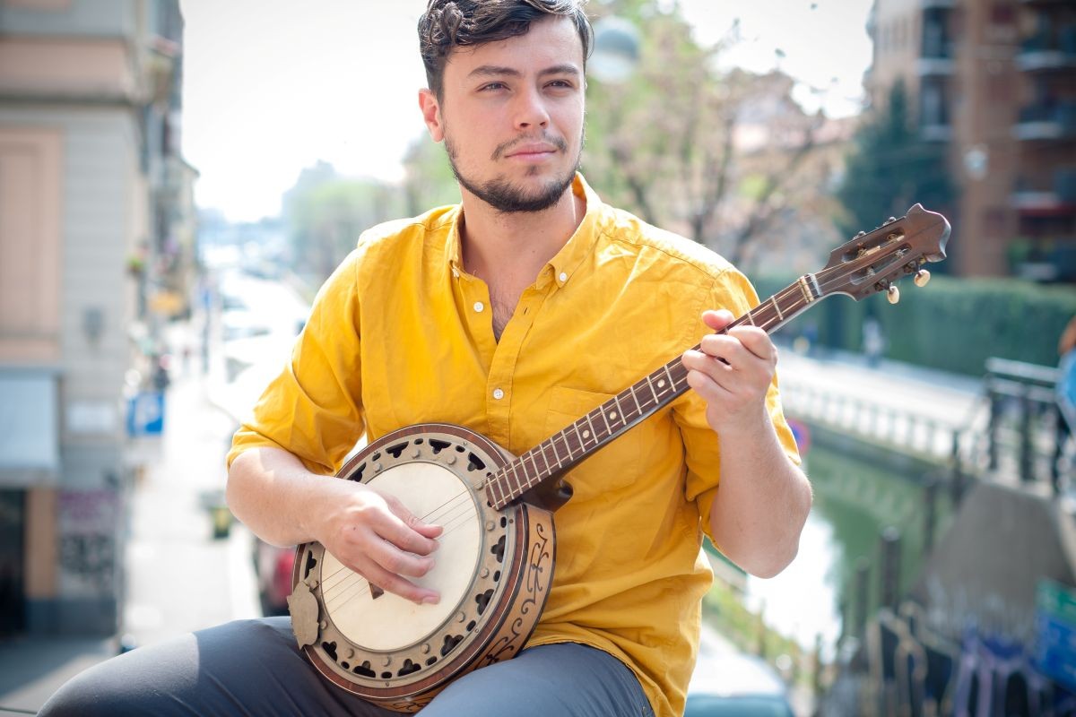 Male playing the Banjo outside on a balcony